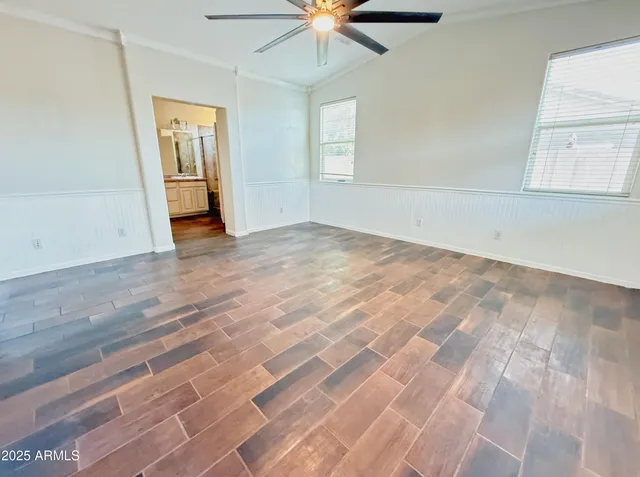 an empty room with chandelier fan and windows
