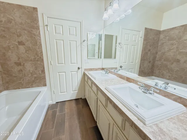 a bathroom with a granite countertop sink a mirror and a bathtub