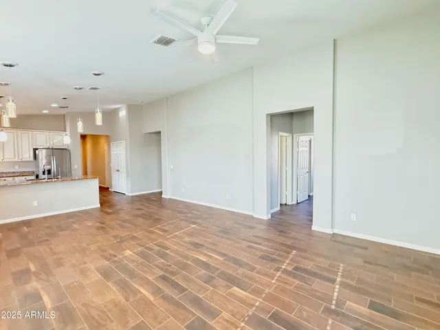 a view of an empty room with kitchen view and a window