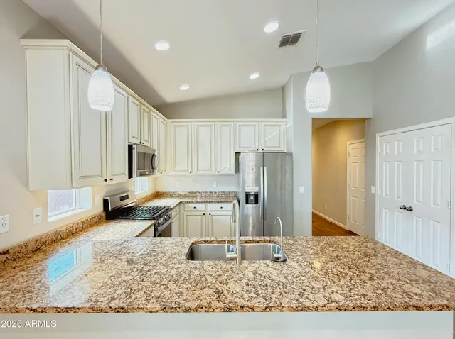 a kitchen with stainless steel appliances kitchen island granite countertop a refrigerator stove oven and white cabinets