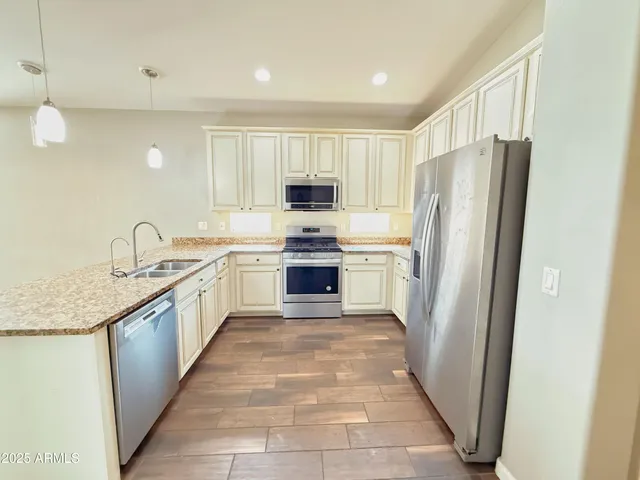 a kitchen with a refrigerator a sink and a stove top oven with wooden floor