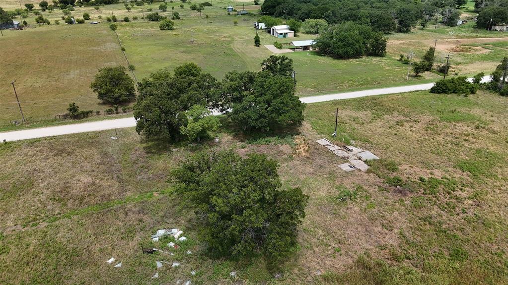 497 Big Sandy Road Newcastle, TX 76372 - Photo 8 of 22 Outdoor water spigot with a blue handle, situated in a field of natural grasses, surrounded by mature trees in the distance