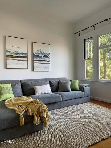 a living room with a bed painting on the wall and a window