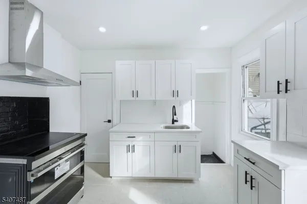 a kitchen with stainless steel appliances white cabinets and a stove top oven