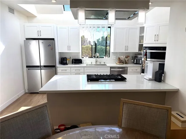 a kitchen with kitchen island a white counter top space a refrigerator and a sink