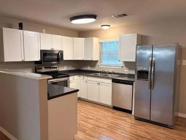 a kitchen with granite countertop a refrigerator stove top oven and sink