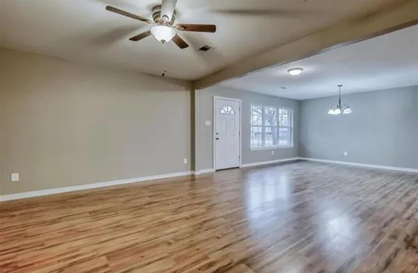a view of an empty room with window and wooden floor