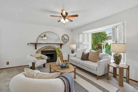 a living room with furniture a fireplace and a large window