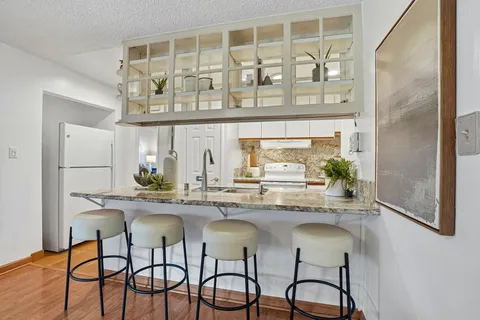 a kitchen with stainless steel appliances granite countertop a table and chairs in it