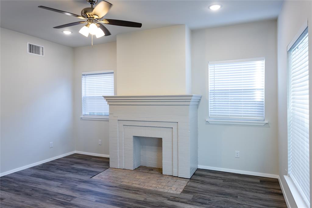 4522 Reiger Avenue Dallas, TX 75246 - Photo 17 of 37 Unfurnished living room featuring a wealth of natural light, a fireplace, and dark hardwood / wood-style flooring