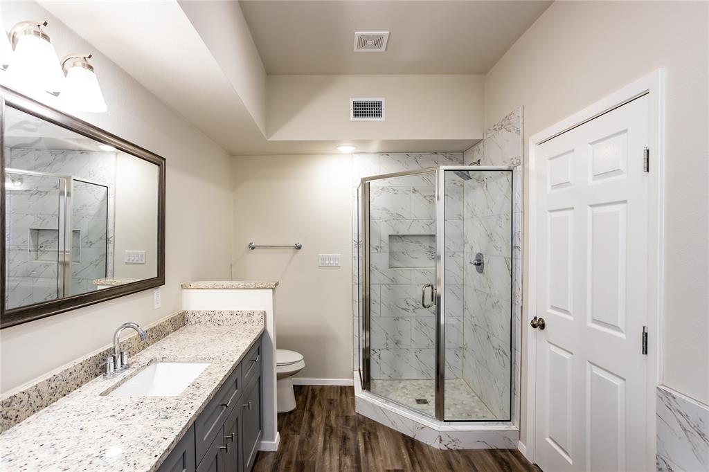 4522 Reiger Avenue Dallas, TX 75246 - Photo 33 of 37 Bathroom featuring a shower with door, vanity, wood-type flooring, and toilet