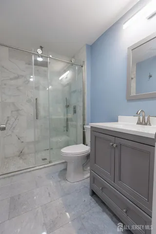 a bathroom with a toilet a sink a mirror and shower