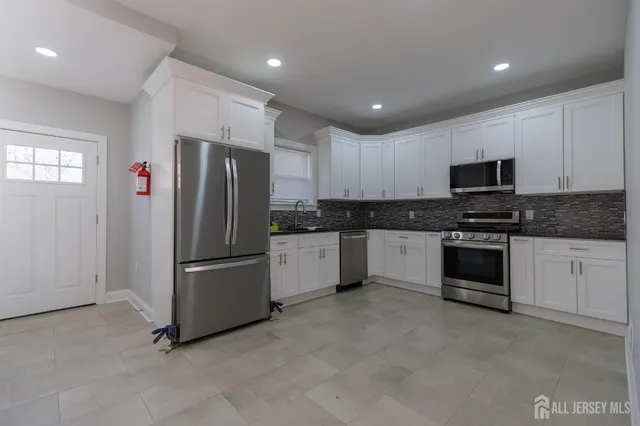 a kitchen with granite countertop white cabinets and stainless steel appliances