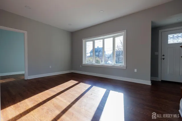 a view of an empty room and wooden floor and a window