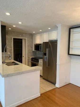 a kitchen with stainless steel appliances granite countertop a refrigerator a sink a stove and oven