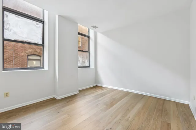 an empty room with wooden floor and windows