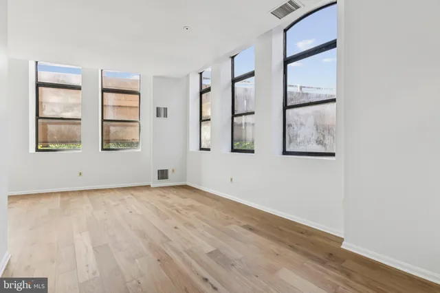 an empty room with wooden floor and windows