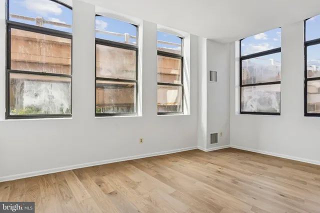 an empty room with wooden floor and windows