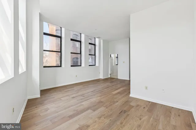 an empty room with wooden floor and windows