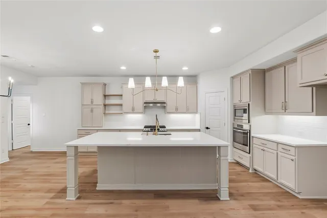 a large kitchen with kitchen island a stove a sink dishwasher and a refrigerator with wooden floor