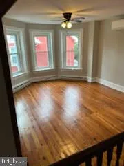 a view of an empty room with wooden floor and windows