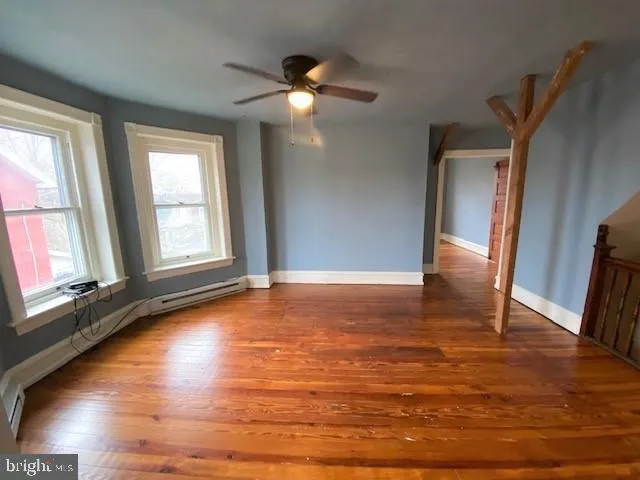 a view of an empty room with window and wooden floor