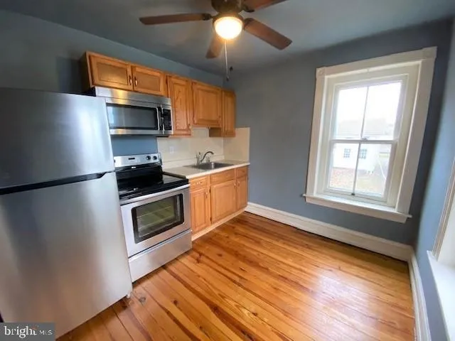 a kitchen with stainless steel appliances a stove a microwave and a hard wood floor