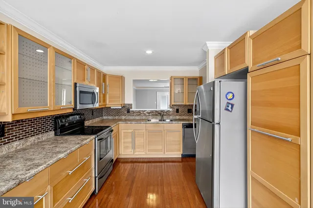 a kitchen with stainless steel appliances granite countertop a refrigerator a stove and a sink with wooden floor