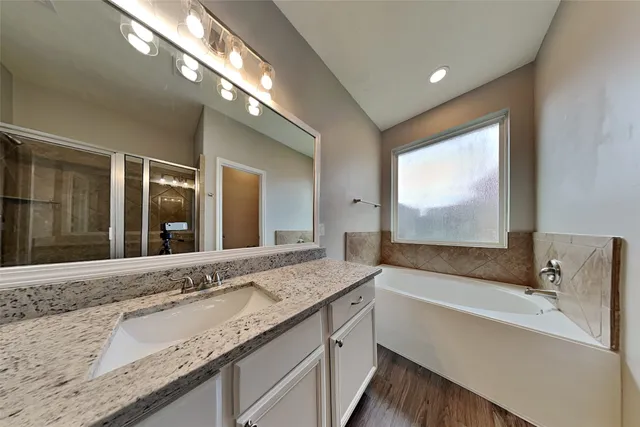 a bathroom with a granite countertop sink and mirror with bathtub
