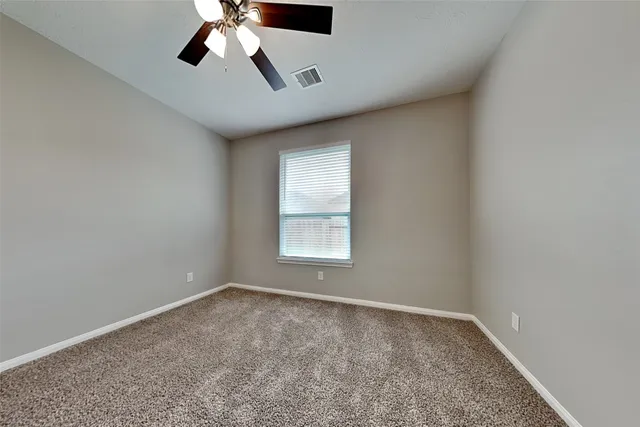 an empty room with a window and a fan