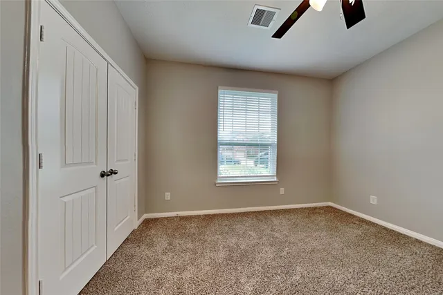 an empty room with ceiling fan and windows