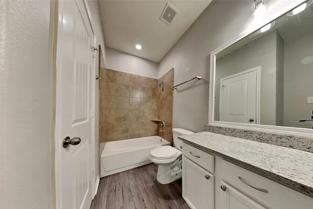 a bathroom with a granite countertop sink a toilet and shower