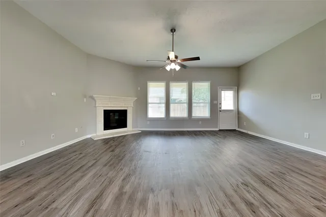 an empty room with wooden floor fireplace and windows