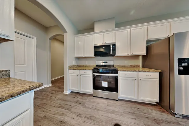 a kitchen with granite countertop a refrigerator stove and sink
