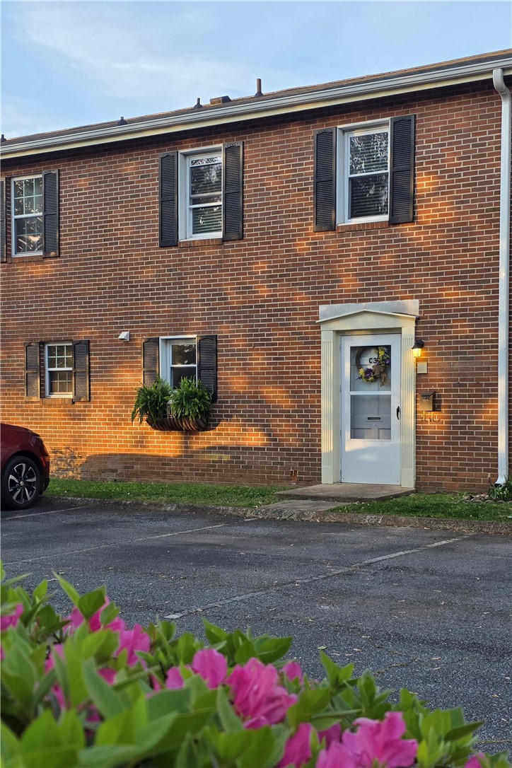 This classic brick structure features traditional black shutters and a welcoming front entrance.