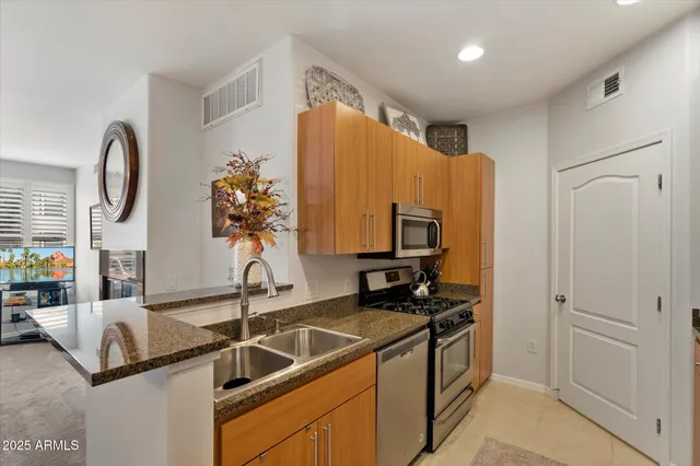 a kitchen with stainless steel appliances granite countertop a sink and a refrigerator