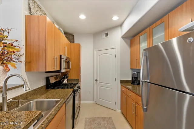 a kitchen with stainless steel appliances granite countertop a refrigerator a sink and a stove