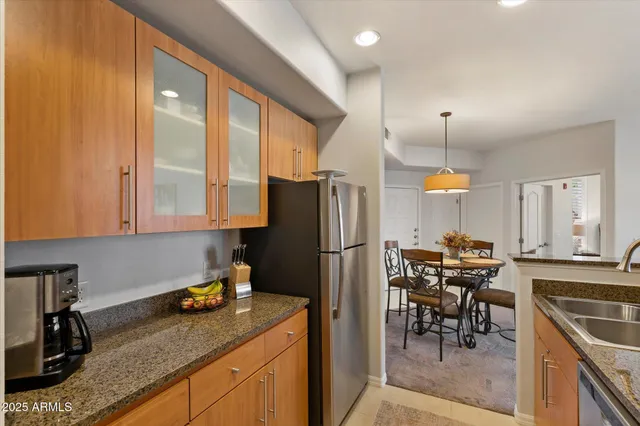 a kitchen with a refrigerator a stove a sink and a dining table with chairs