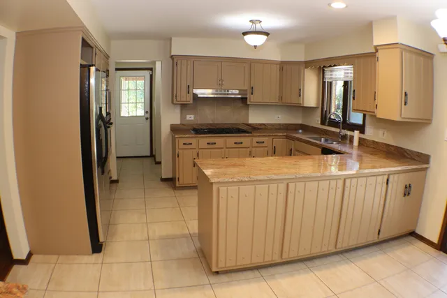 a kitchen with stainless steel appliances granite countertop a sink and a refrigerator
