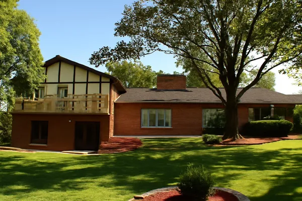 a view of a house with a big yard and large trees