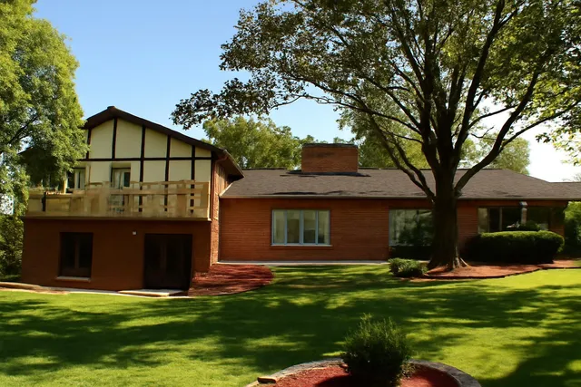 a view of a house with a big yard and large trees