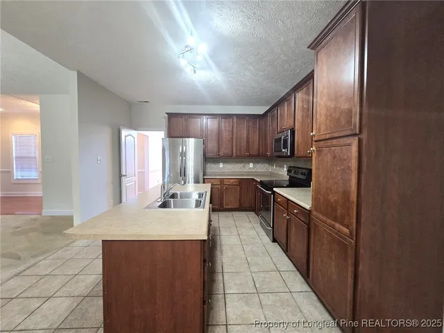 a kitchen with stainless steel appliances granite countertop a sink refrigerator and cabinets