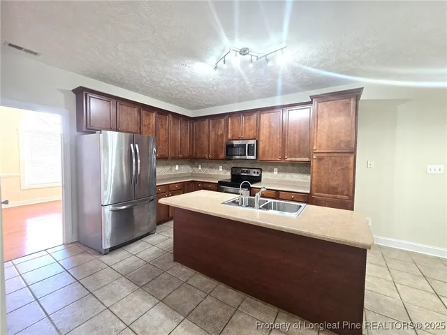 a kitchen with stainless steel appliances granite countertop a refrigerator a sink a stove a washer and dryer