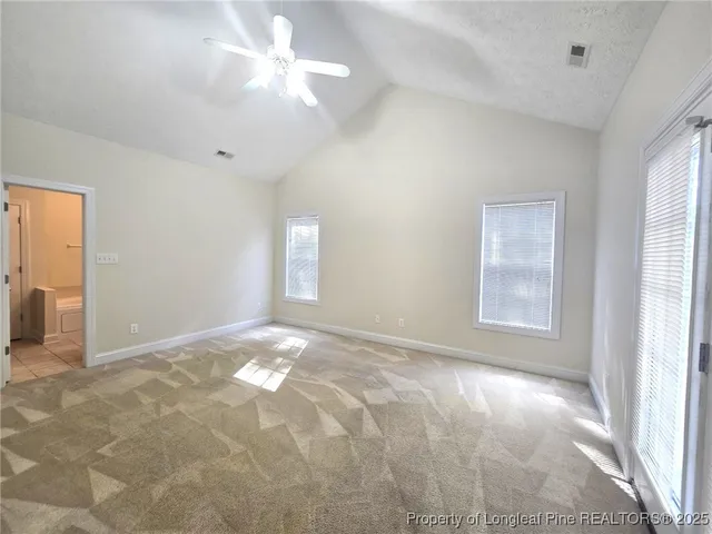 a view of an empty room with chandelier fan and fire place