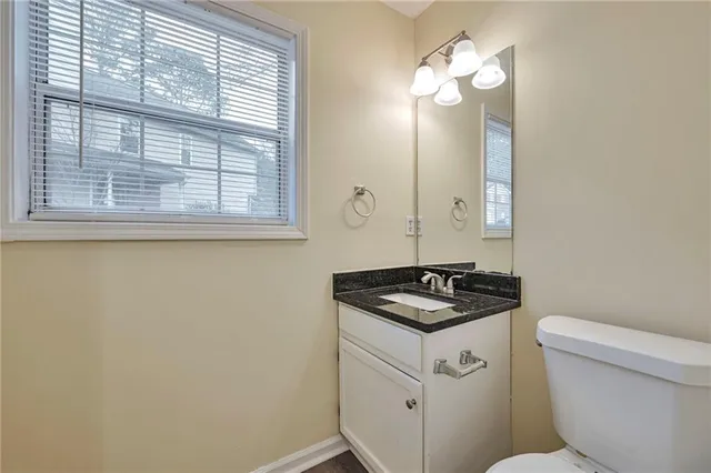 a bathroom with a granite countertop sink and a toilet