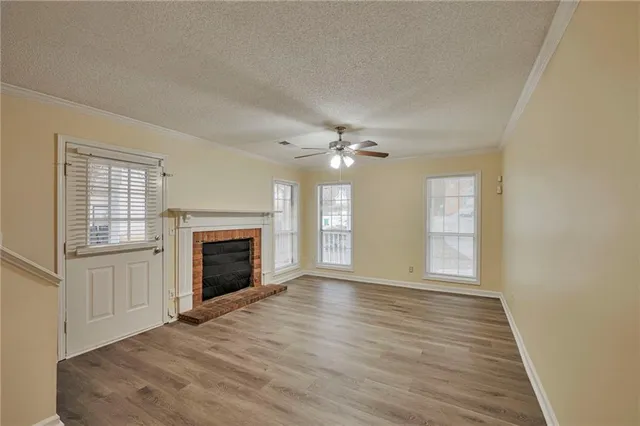 an empty room with windows fireplace and wooden floor