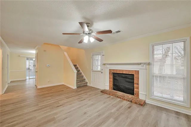 an empty room with wooden floor fireplace and windows