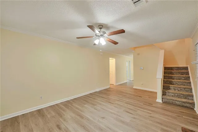 an empty room with wooden floor ceiling fan and window
