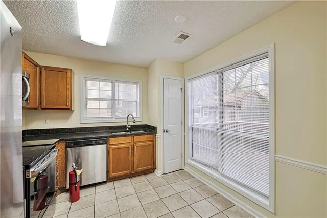 a kitchen with granite countertop a stove a sink and a refrigerator