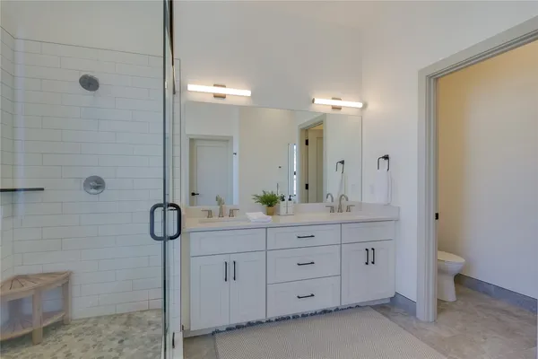 a bathroom with a double vanity sink a large mirror and shower